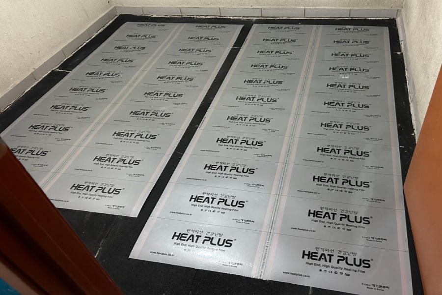 Vista de la película de calefacción radiante de Pisos Calidos instalada bajo el suelo, mostrando cableado seguro y sensor de temperatura para un hogar cálido y eficiente.